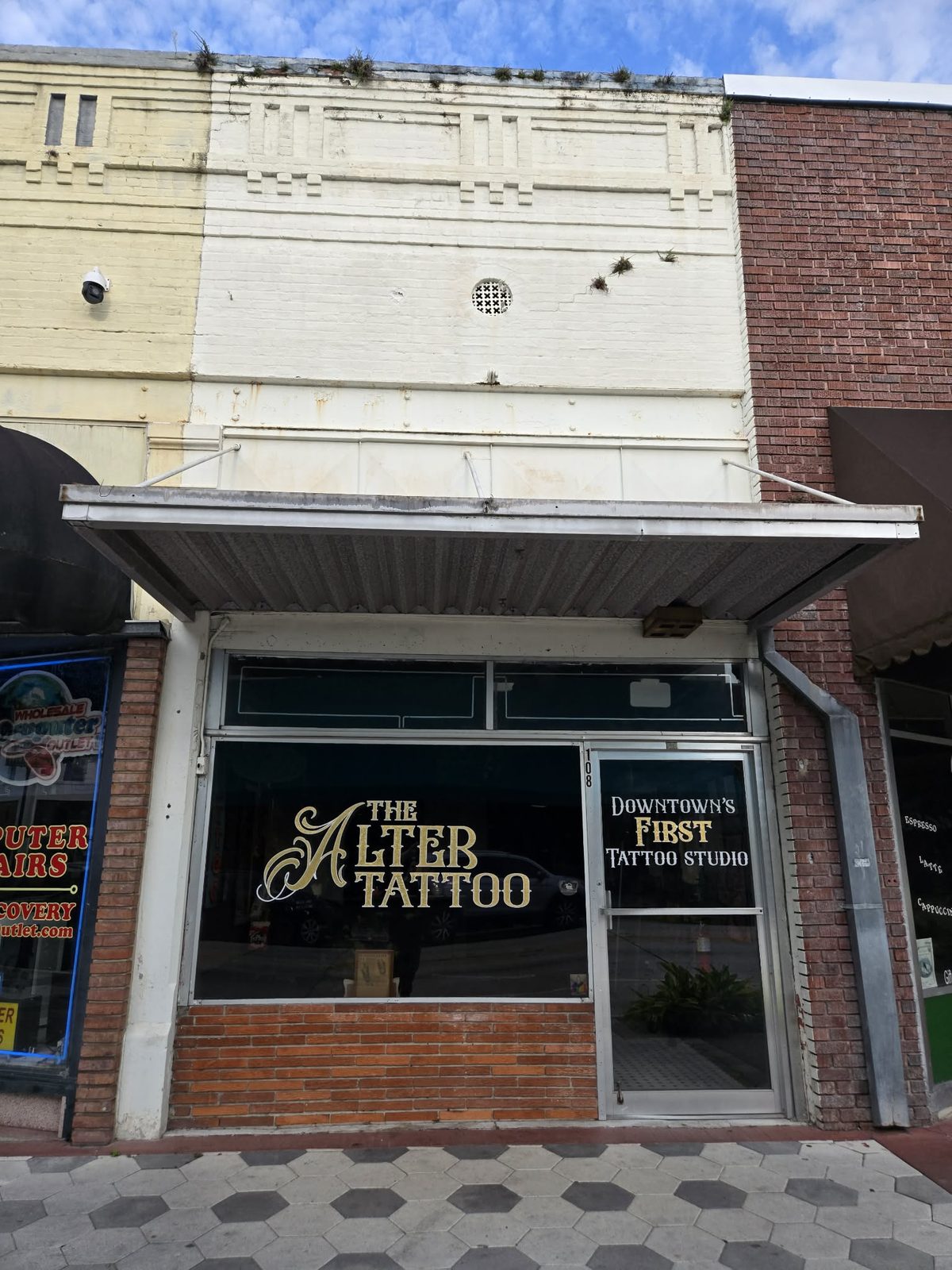 Storefront of The Alter Tattoo studio with gold window lettering in downtown DeLand.