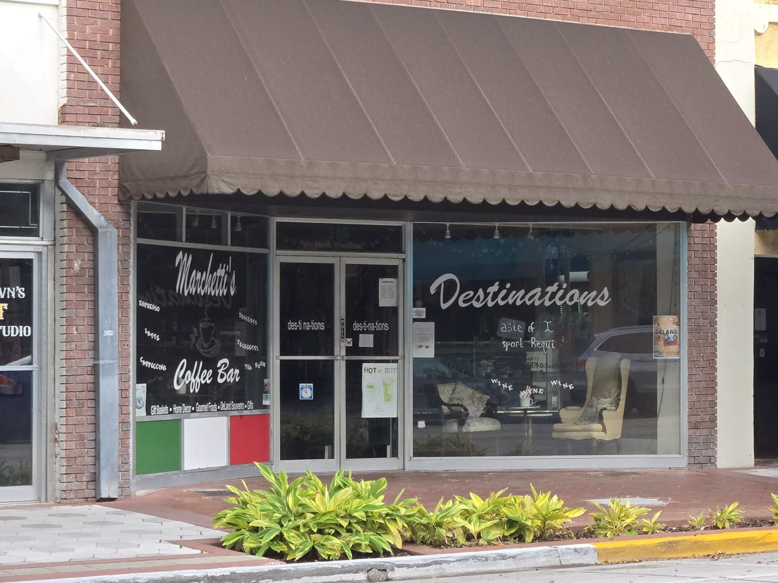 Storefront of Destinations and Marchetti's Coffee Bar with a brown awning in downtown DeLand.