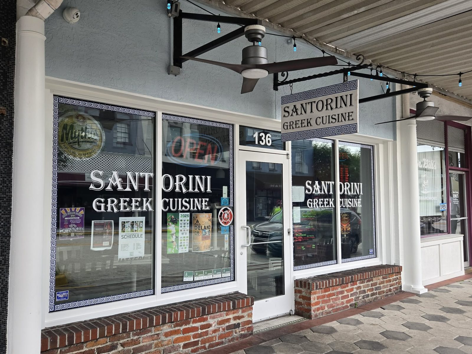 Storefront with a hanging Santorini Greek Cuisine sign and Greek-key windows in downtown DeLand.
