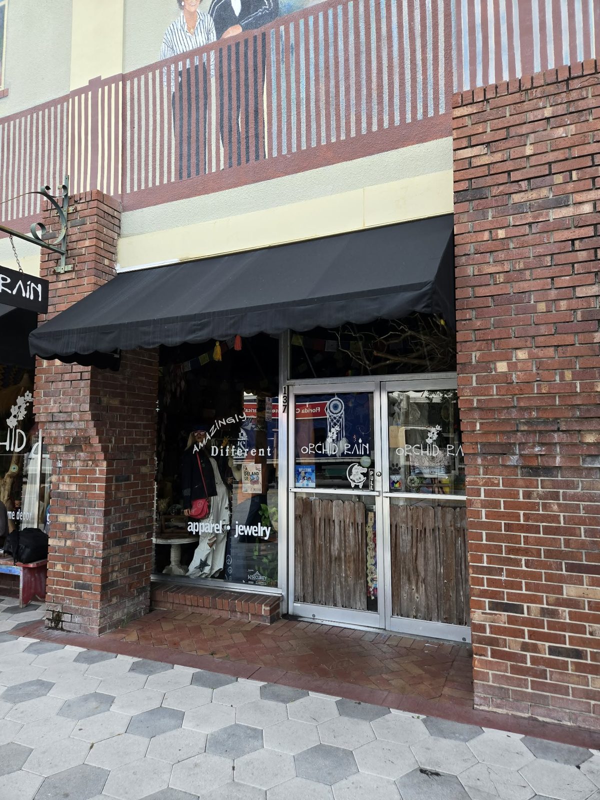 Brick storefront with a black awning for the Orchid Rain apparel and jewelry boutique in downtown DeLand.