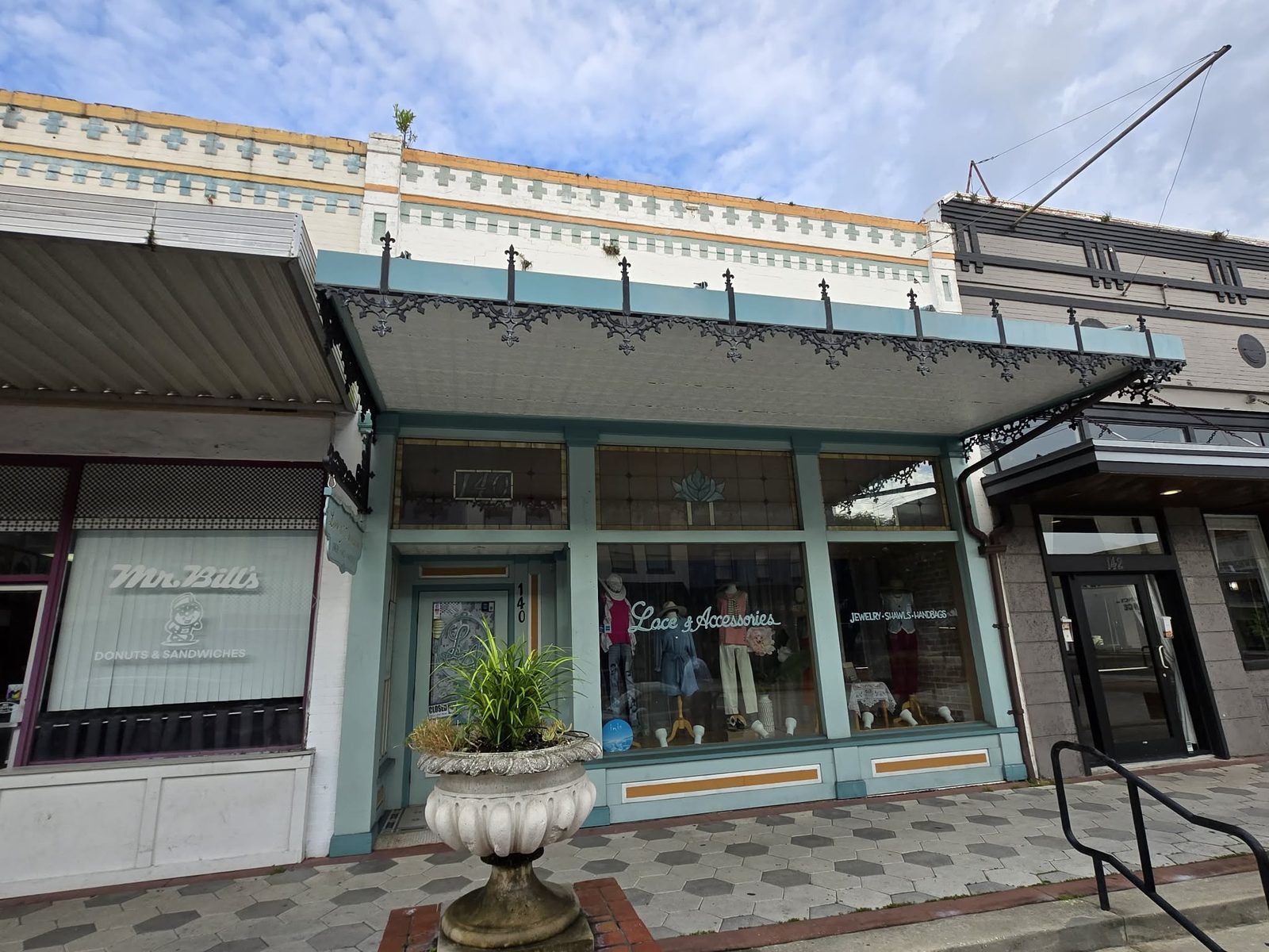 Turquoise storefront with an iron awning and a Lace and Accessories window display in downtown DeLand.