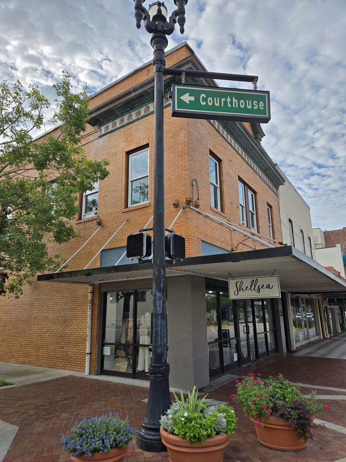 Corner brick building with a Shellsea women's boutique sign above glass storefront doors in downtown DeLand.