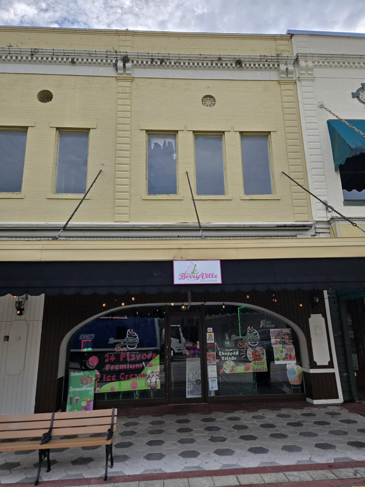 Yellow storefront with a pink BerryVille ice cream sign above an arched window in downtown DeLand.