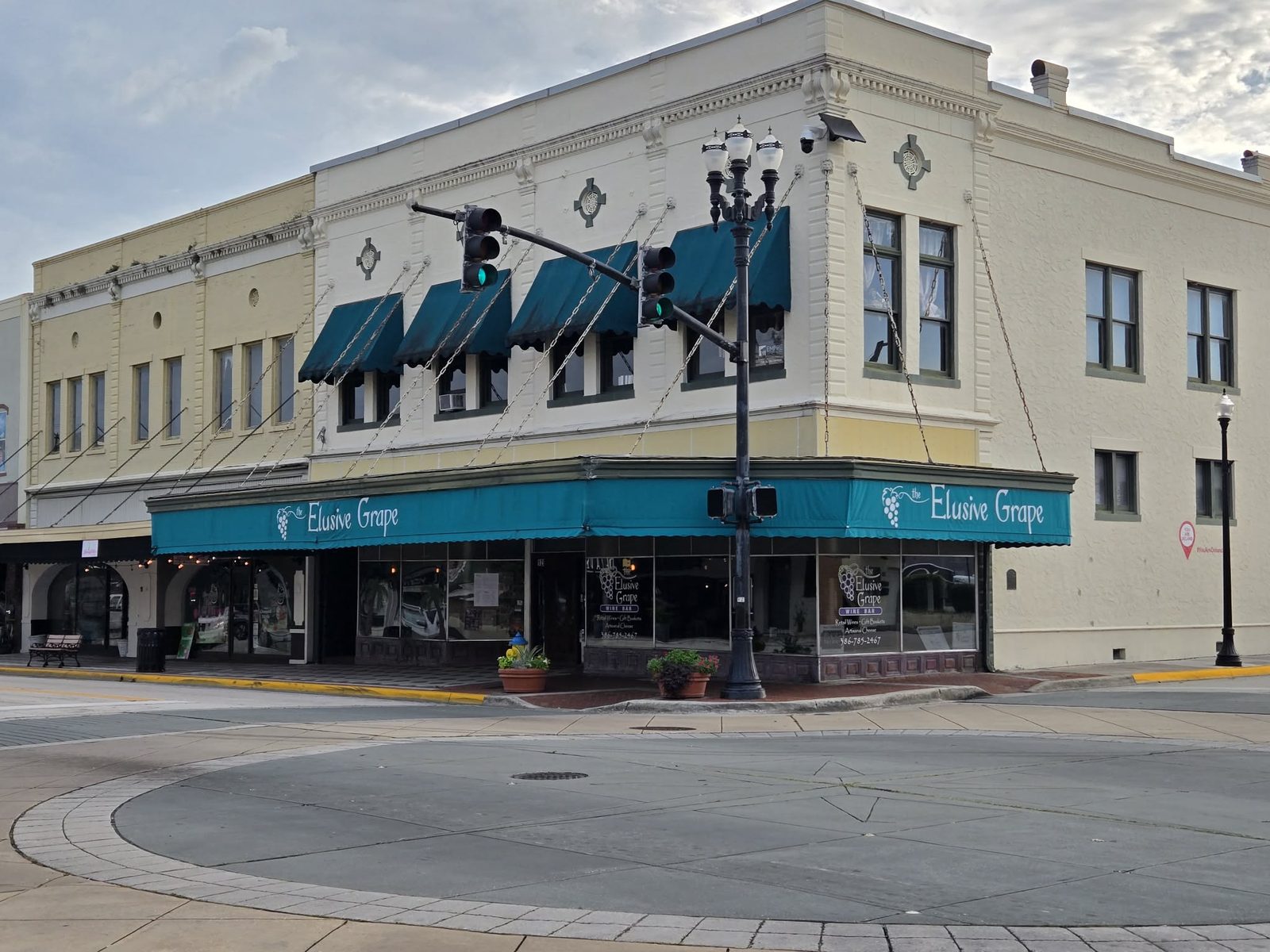 Cream corner building with teal awnings for the Elusive Grape wine bar in downtown DeLand.