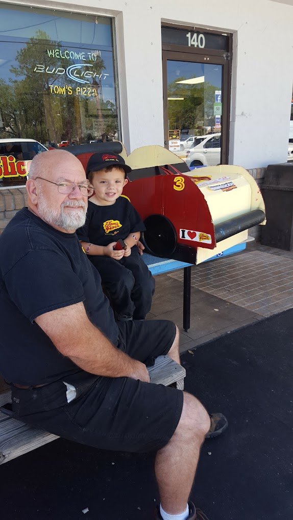 The Tom's Pizza storefront and sign at 140 E Rich Ave in DeLand, with longtime owner Lloyd Petro outside the shop