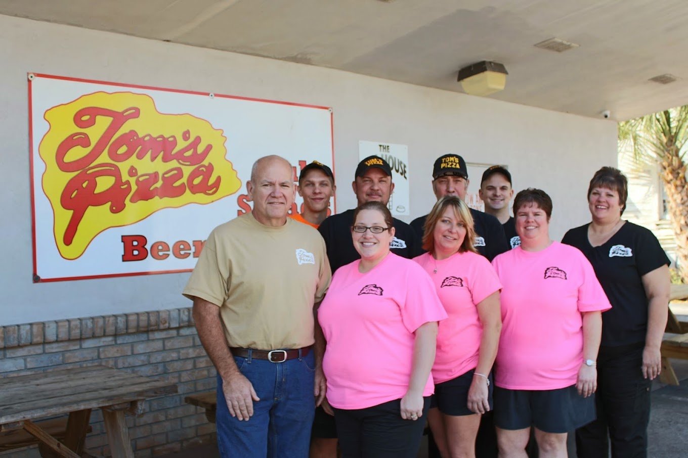 The Tom's Pizza team at the Tom's Pizza sign in DeLand