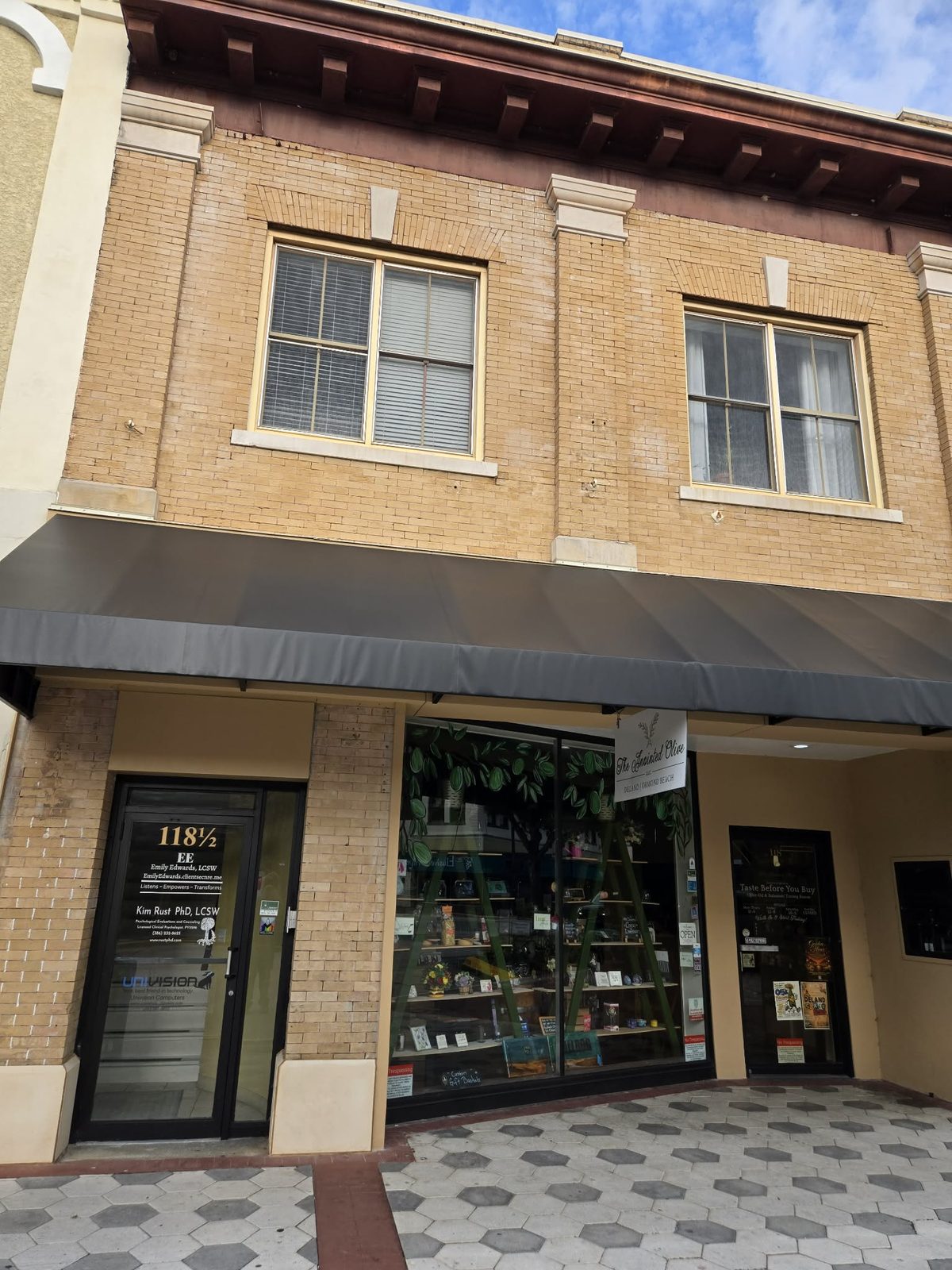 Storefront of The Anointed Olive olive oil shop with a gray awning in downtown DeLand.
