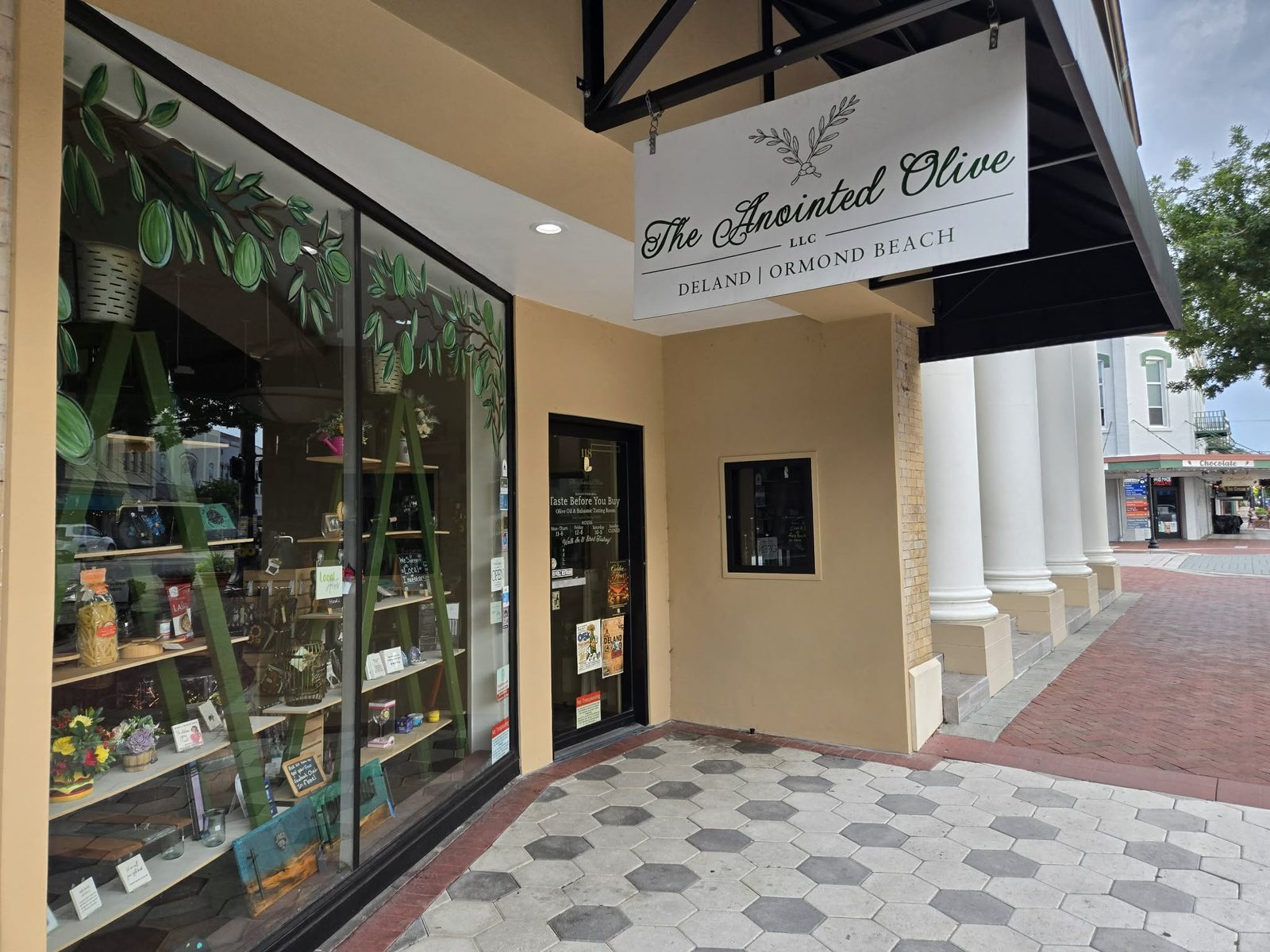 Hanging sign and window display of The Anointed Olive shop in downtown DeLand.