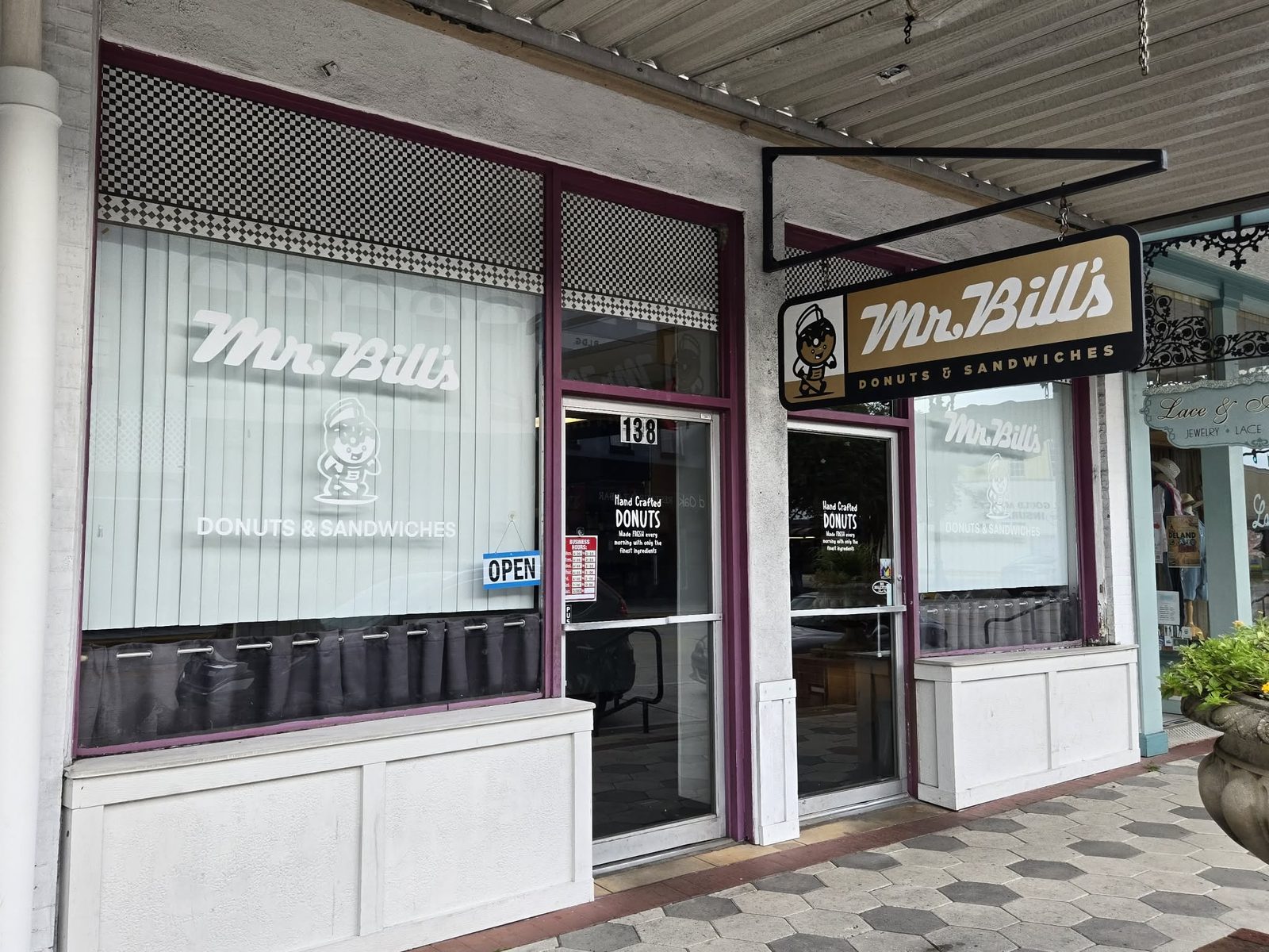Storefront lettered Mr. Bill's Donuts and Sandwiches with a projecting donut-mascot sign in downtown DeLand.