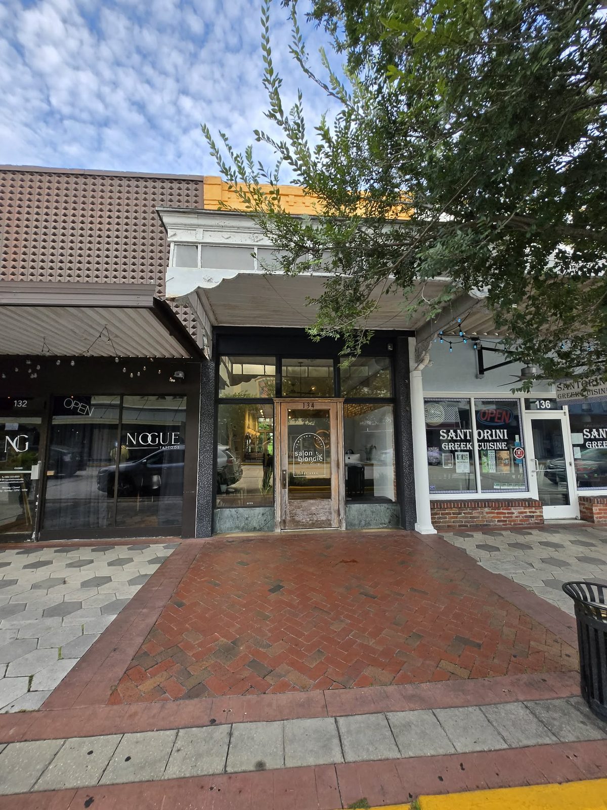 Narrow storefront with a Salon Blondie glass door flanked by neighboring shops in downtown DeLand.