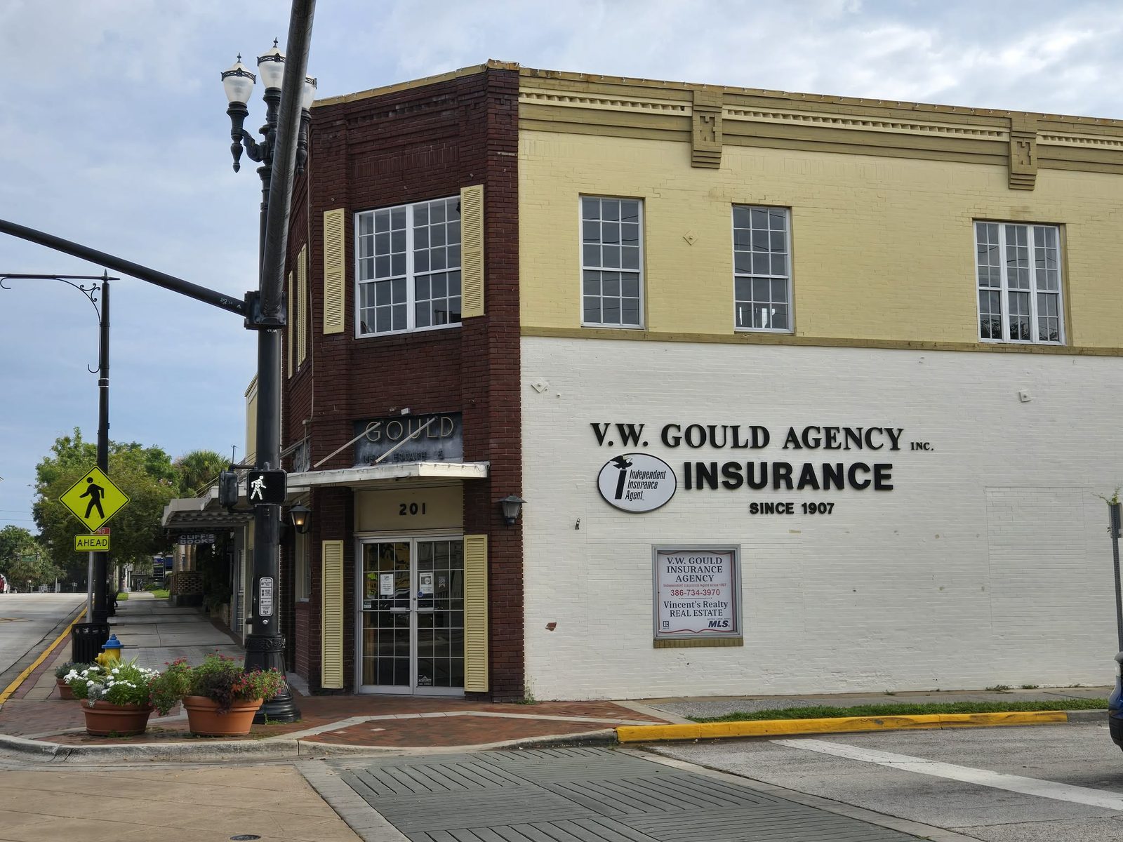 Corner brick building with a large V.W. Gould Agency Insurance wall sign in downtown DeLand.