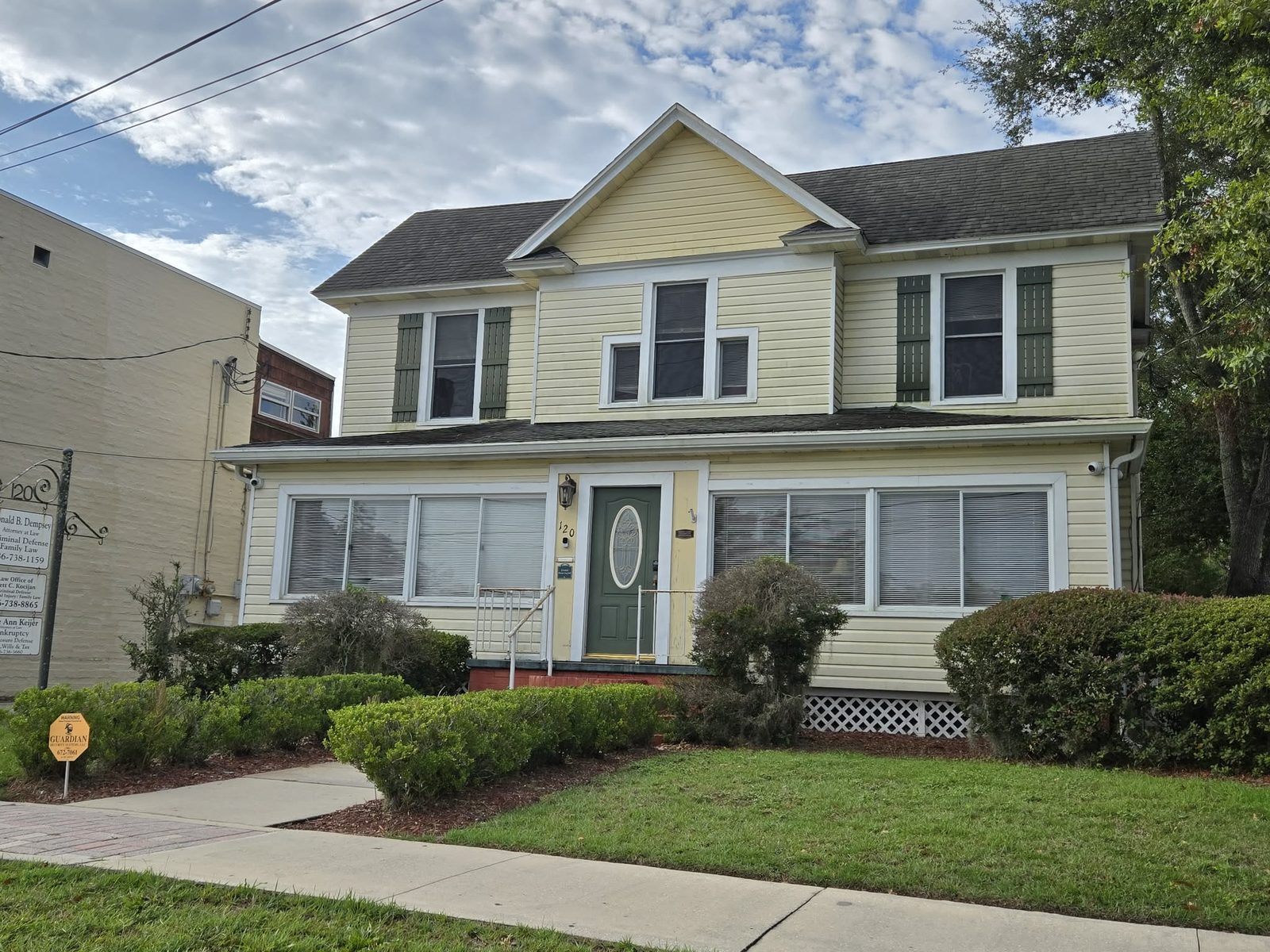 Two-story yellow historic house serving as Donald B. Dempsey's law office in downtown DeLand.