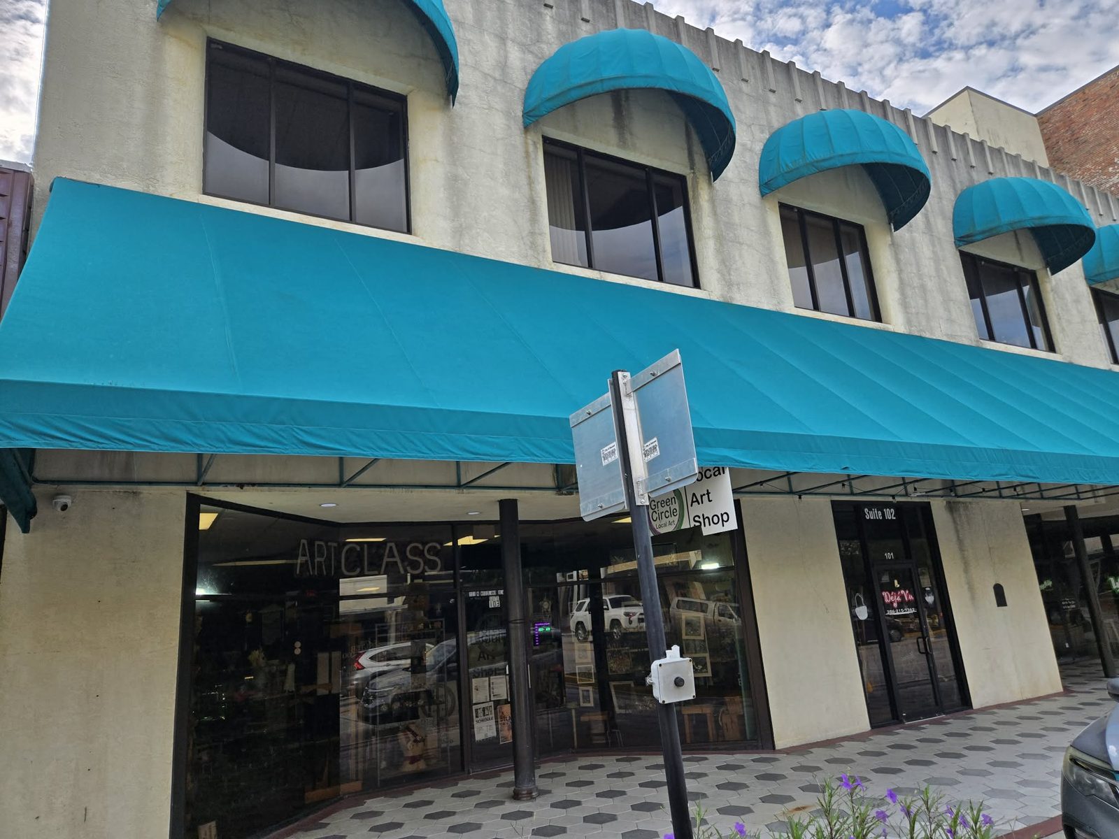 Storefront of Green Circle local art shop with bright teal awnings in downtown DeLand.